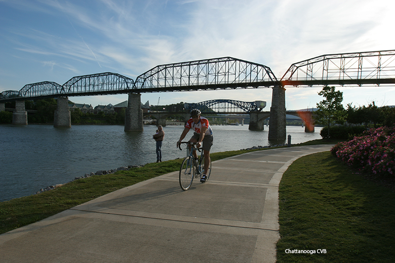Bicyclist riding along Chattanooga's Riverwalk under downtown bridges. Photo courtesy of Chattanooga CVB.