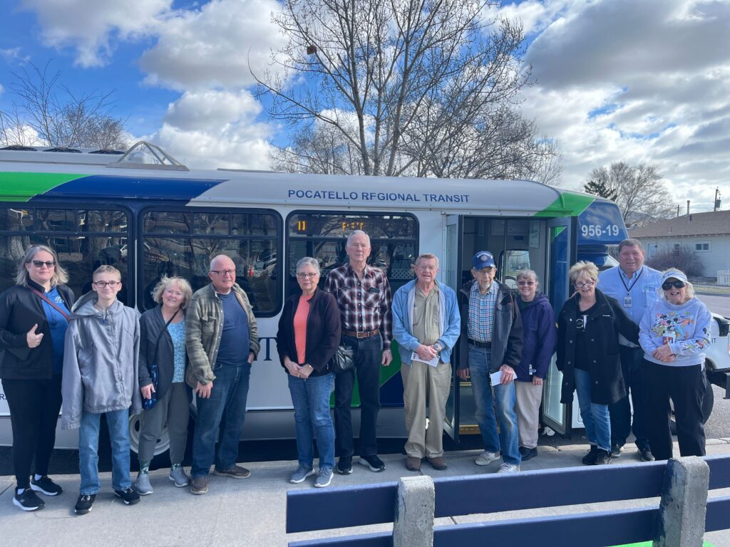 Mixed age group of individuals in front of public transit vehicle